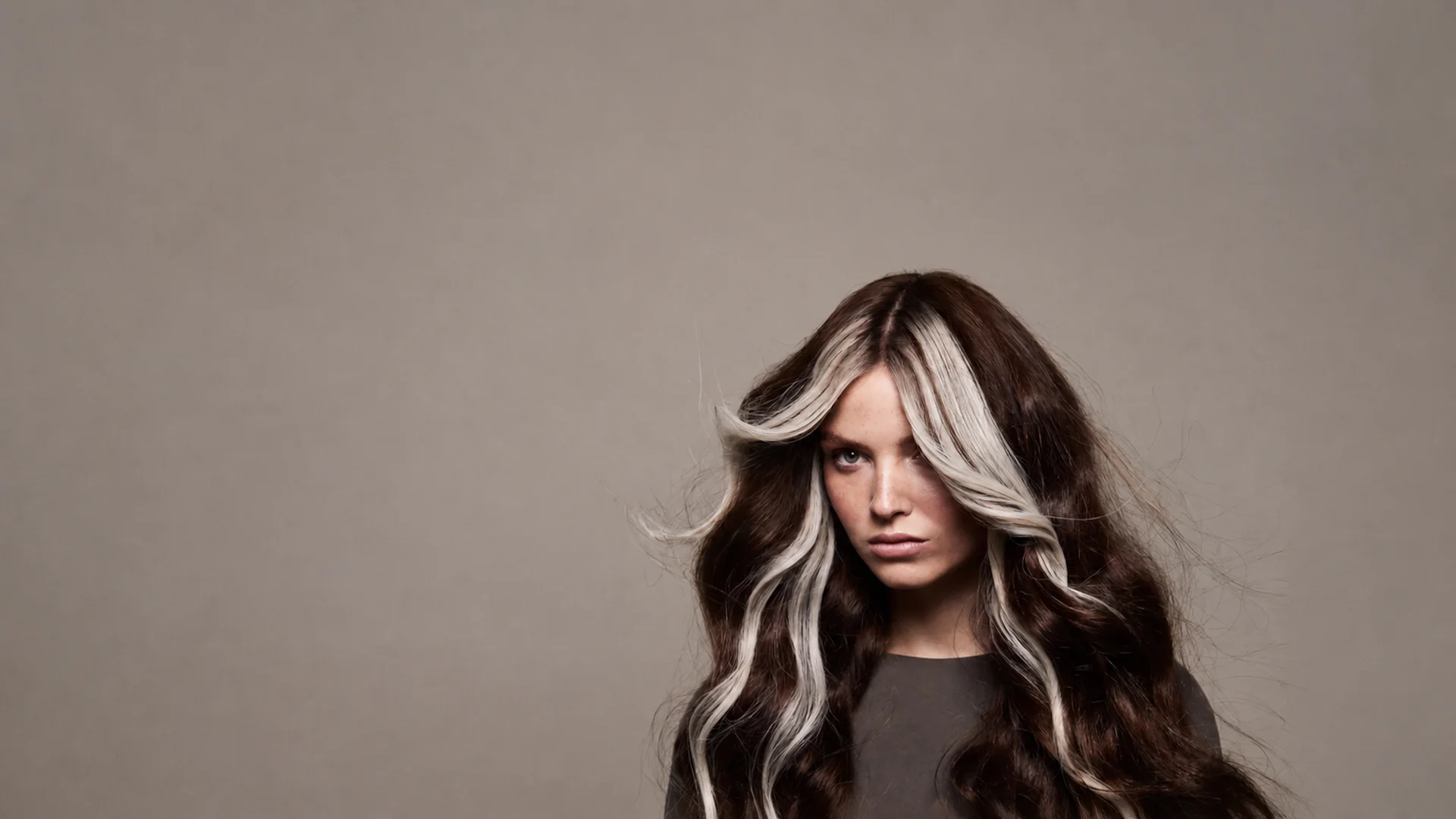 Model with dark hair and cool-beige highlighted sections for the Celine Claire Blonde Hair Routine.