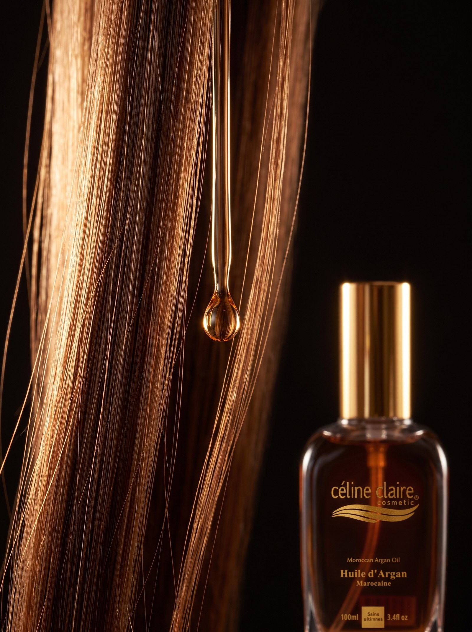 Amber drop of Céline Claire argan oil suspended between polished hair strands