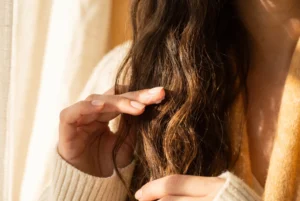 Fingertips lightly skimming dry dark hair ends to control flyaways