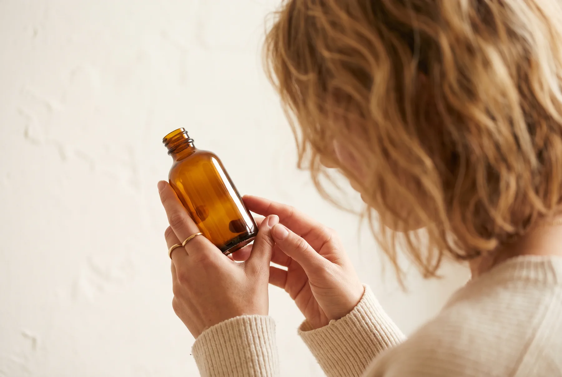 Hands carefully reading the back of a small apothecary bottle before use